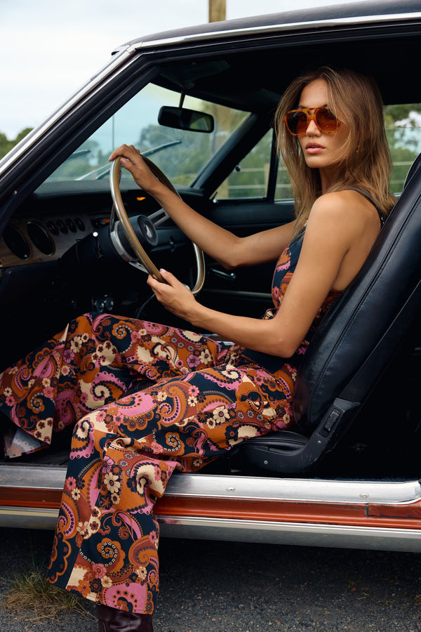Woman sitting in a car wearing a colorful outfit and sunglasses.