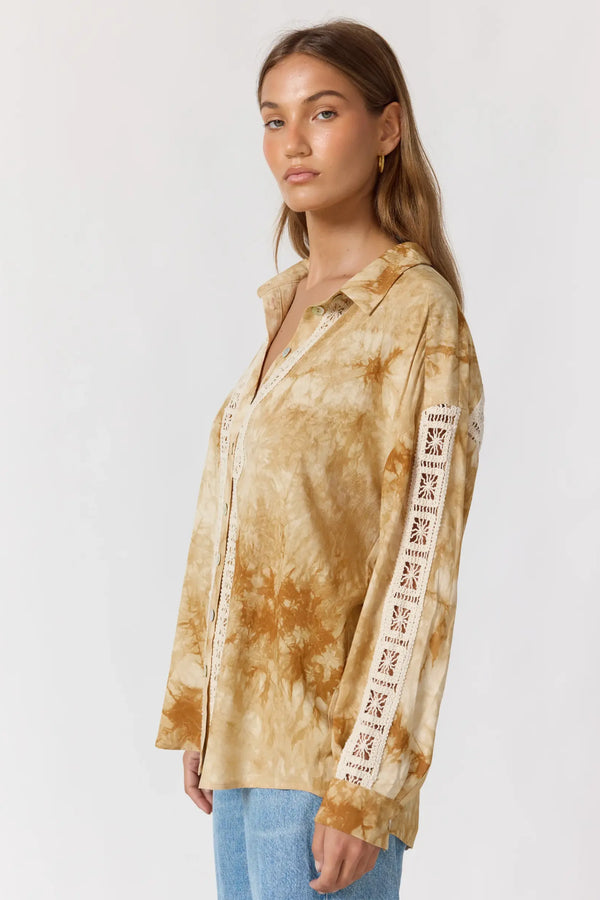 Woman wearing a tie-dye shirt with graphic sleeves on a white background