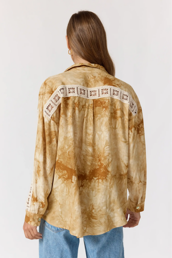 Person wearing a tie-dye shirt with lace details on a white background