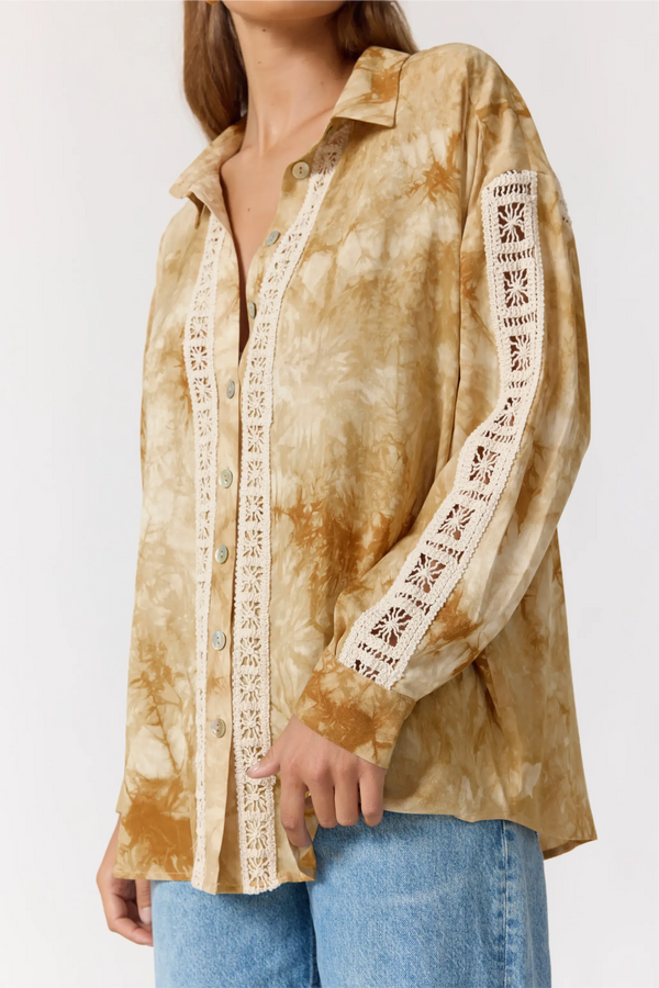 Woman wearing a tie-dye shirt with lace trim on a white background