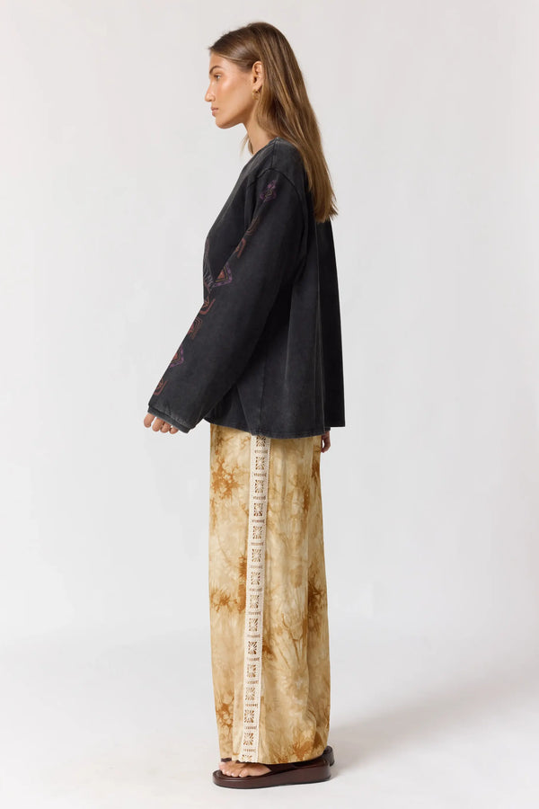 Woman wearing a black top and patterned pants on a white background