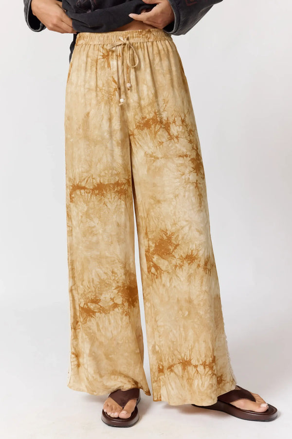 Person wearing tie-dye pants and a dark sweater on a white background