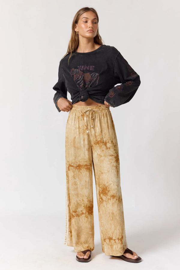 Woman wearing a black sweatshirt and tie-dye pants on a white background