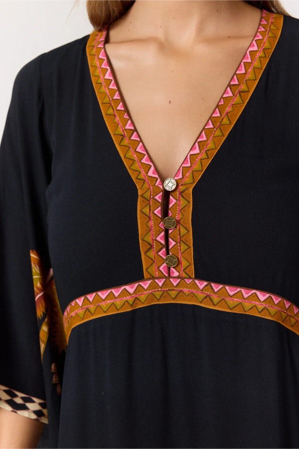 Black dress with colorful geometric embroidery on a plain background