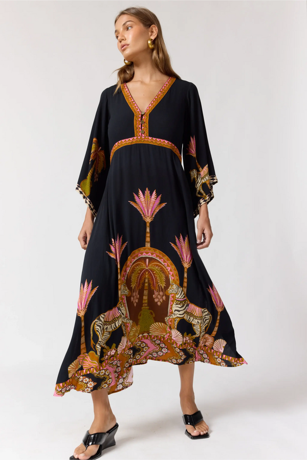 Woman wearing a black dress with intricate floral patterns on a white background