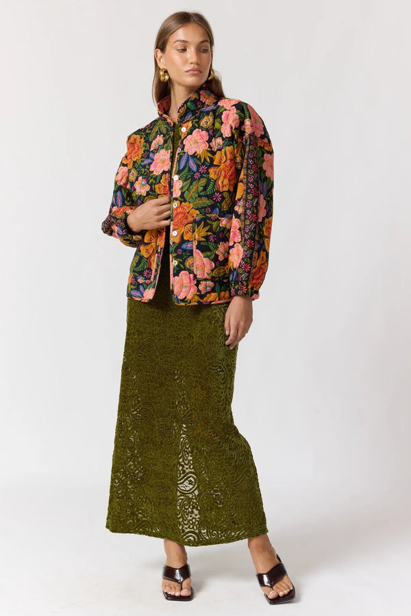Woman wearing a floral jacket and green skirt on a white background