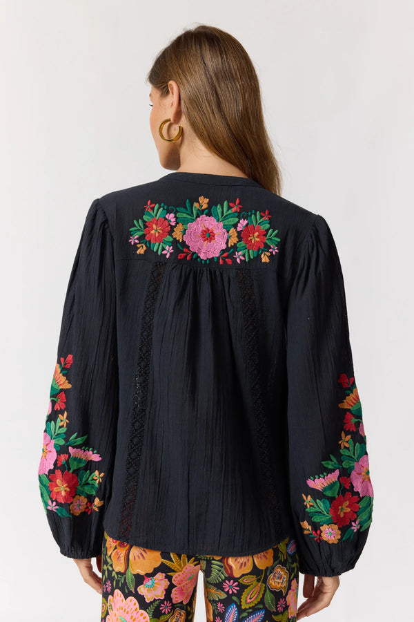 Black blouse with colorful floral embroidery on a white background