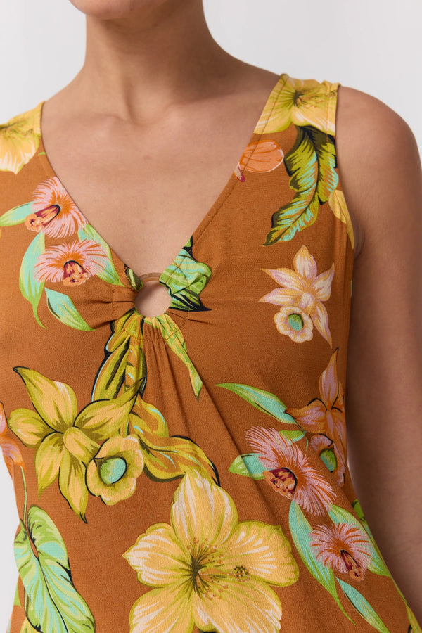 Close-up of a model wearing a brown sleeveless top with a vibrant yellow, green, and pink tropical floral print and a keyhole tie detail at the neckline.