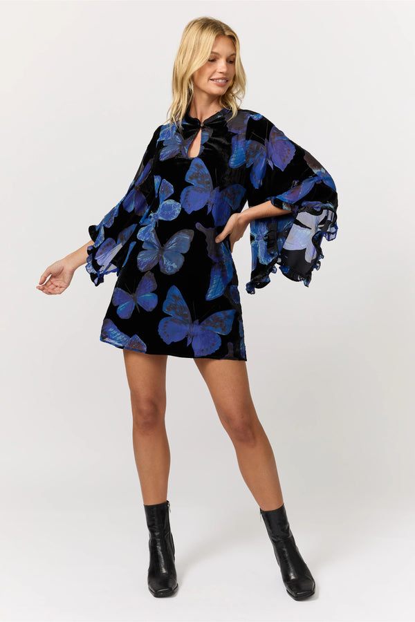 Woman wearing a black dress with blue butterfly patterns on a white background