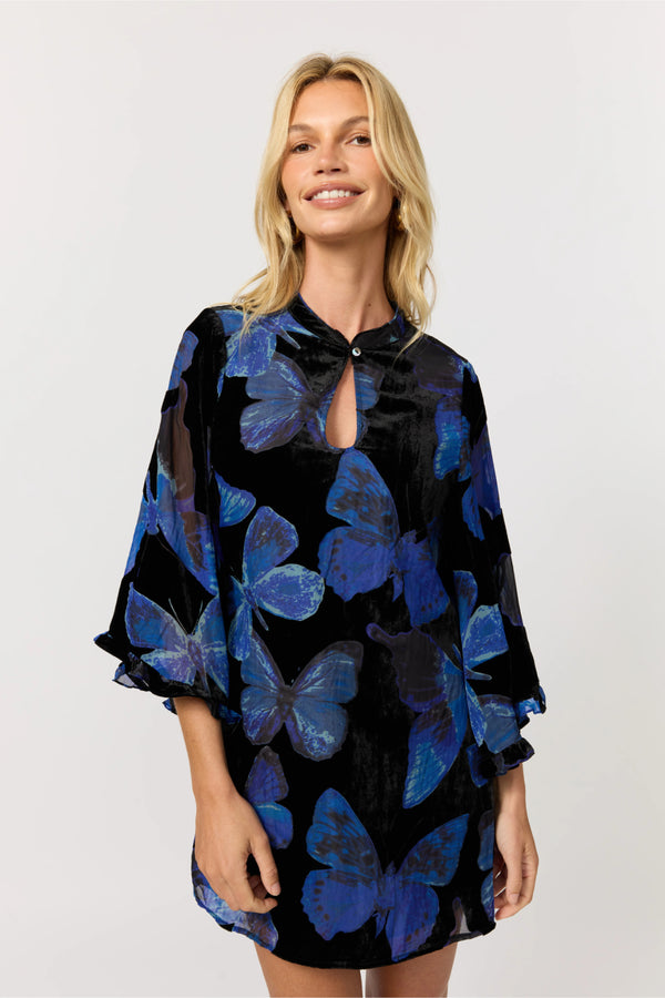 Woman wearing a black dress with blue butterfly patterns on a white background