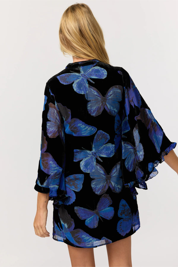 Woman wearing a black kimono with blue butterfly patterns on a white background