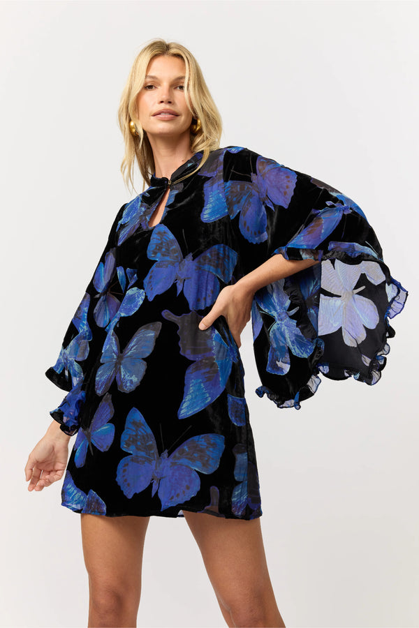 Woman wearing a black dress with blue butterfly patterns on a white background