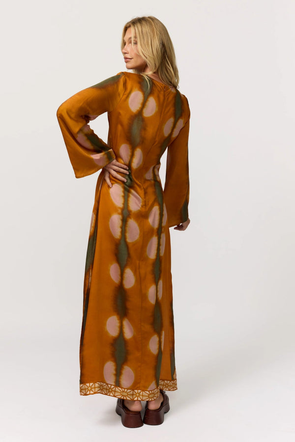 Woman wearing a long, patterned dress on a white background