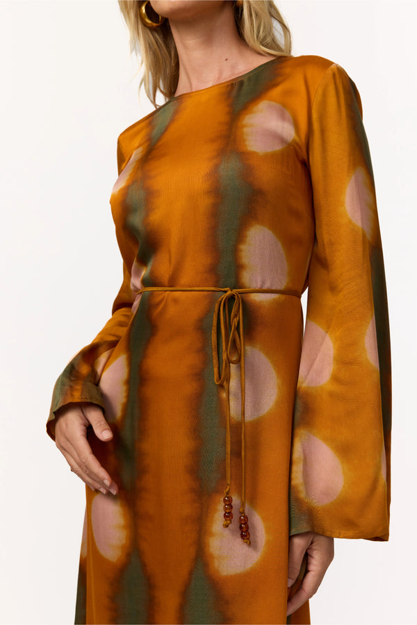 Woman wearing a patterned dress with long sleeves and a drawstring waist.
