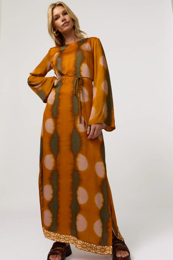 Woman wearing a long, patterned dress against a white background