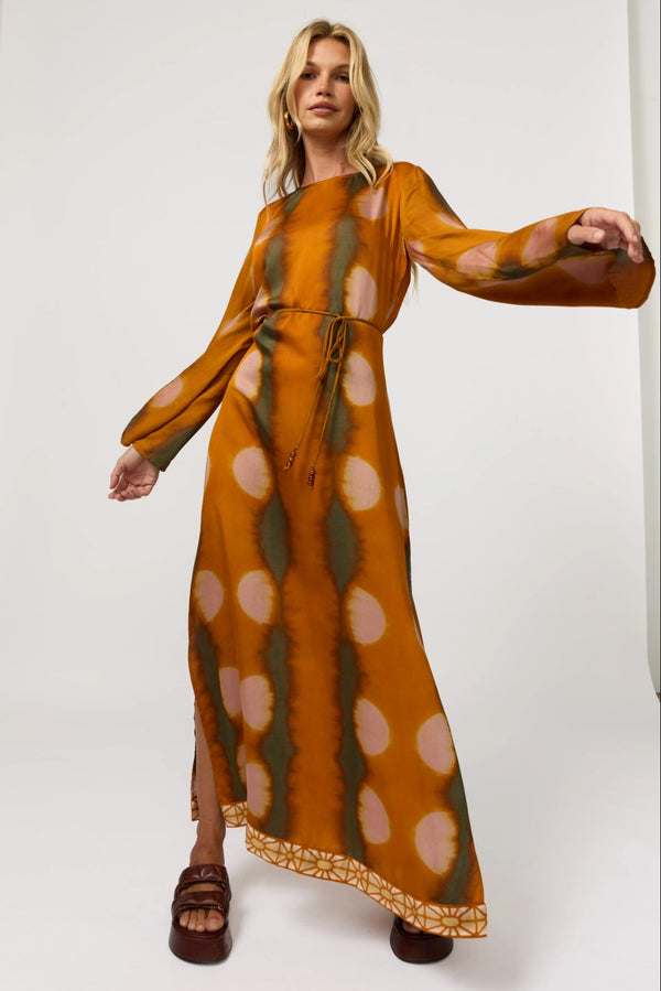 Woman wearing a long, patterned dress against a white background