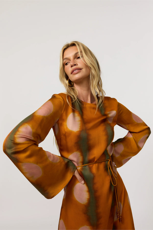 Woman wearing a brown dress with abstract pattern on a white background
