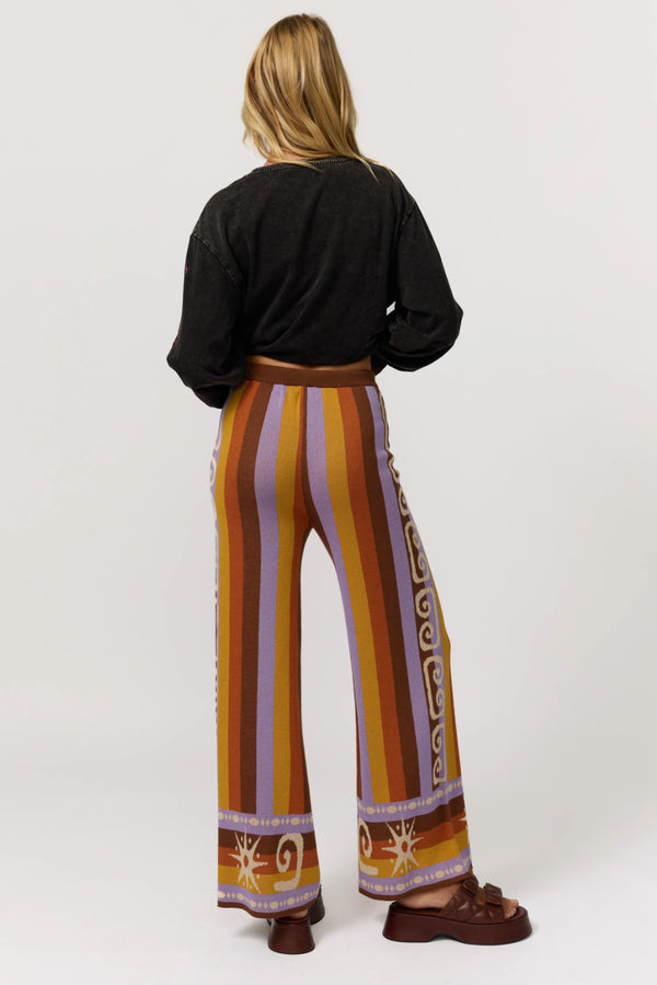 Person wearing a black top and colorful striped pants on a white background