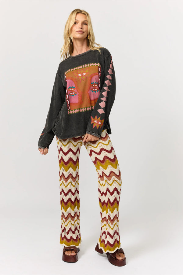 Woman wearing a dark sweater with a colorful pattern and patterned pants on a white background