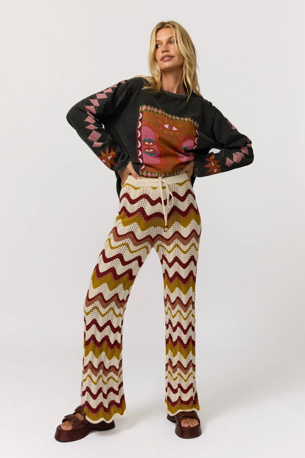 Woman wearing a patterned sweater and chevron pants on a white background