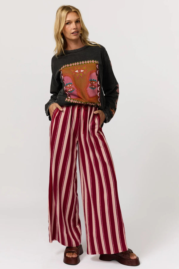Woman wearing a dark sweater with a colorful design and red and white striped pants on a white background