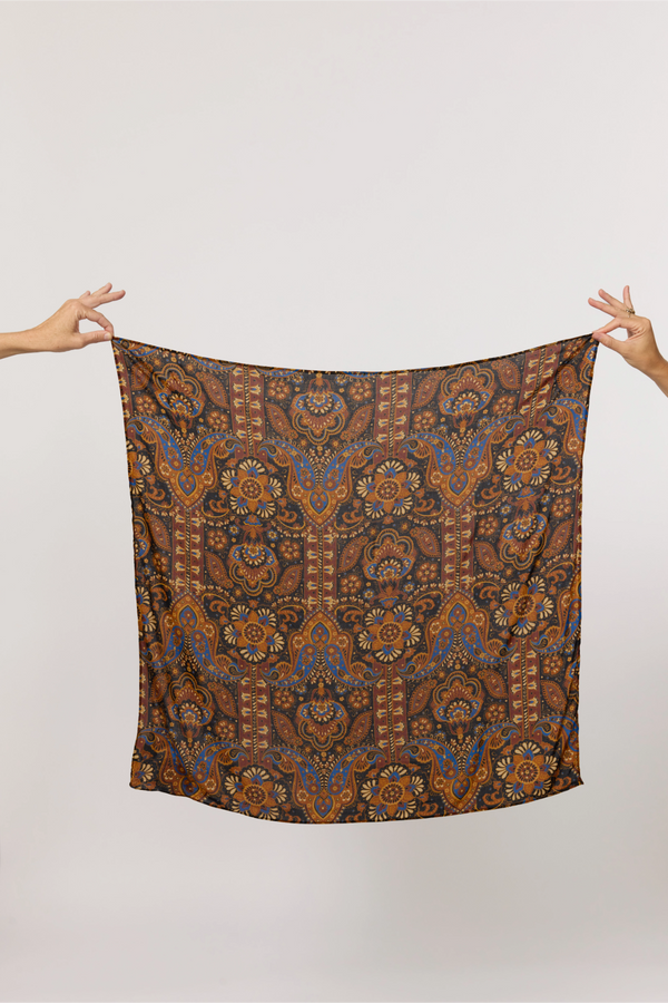 Patterned scarf held by two hands against a plain background