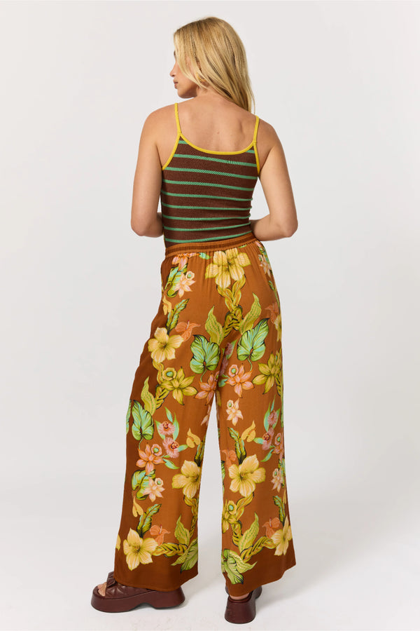Woman wearing a striped tank top and floral pants on a white background