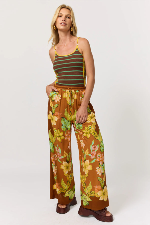 Woman wearing a striped tank top and floral pants on a white background