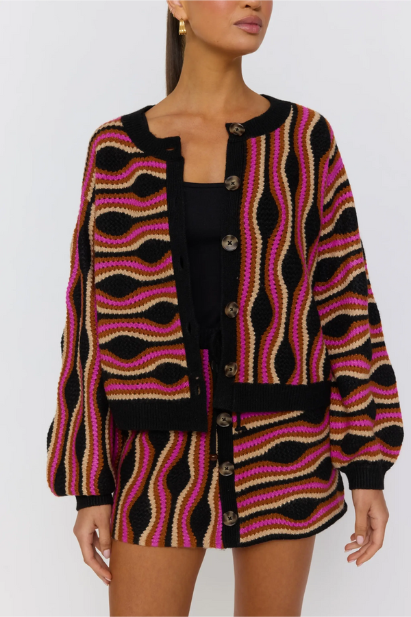 Woman wearing a patterned cardigan with a plain background