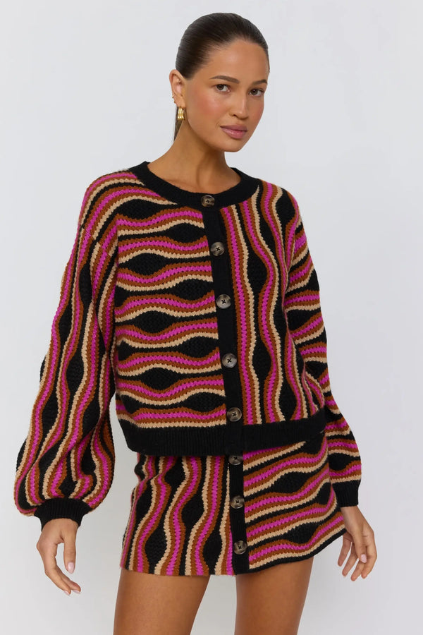 Woman wearing a patterned cardigan and skirt set on a white background