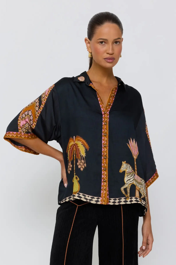 Woman wearing a black blouse with animal print and black pants on a white background