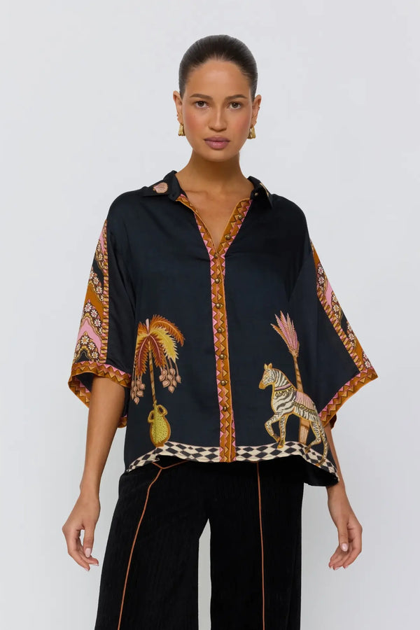 Woman wearing a black blouse with animal prints and black pants on a white background