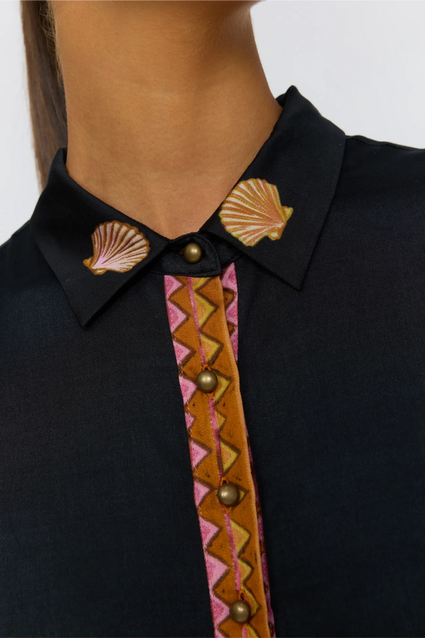 Close-up of a black shirt with decorative shell and geometric patterned tie.