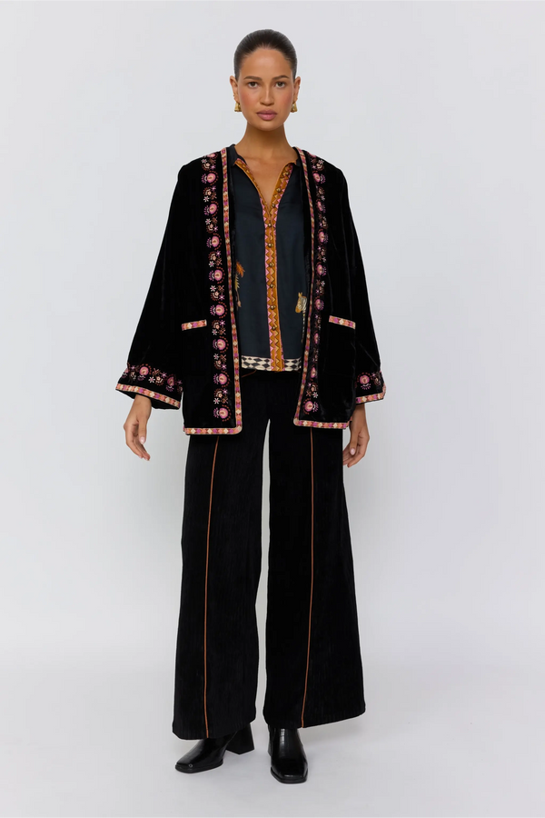 Woman wearing a black outfit with floral embroidery on a white background