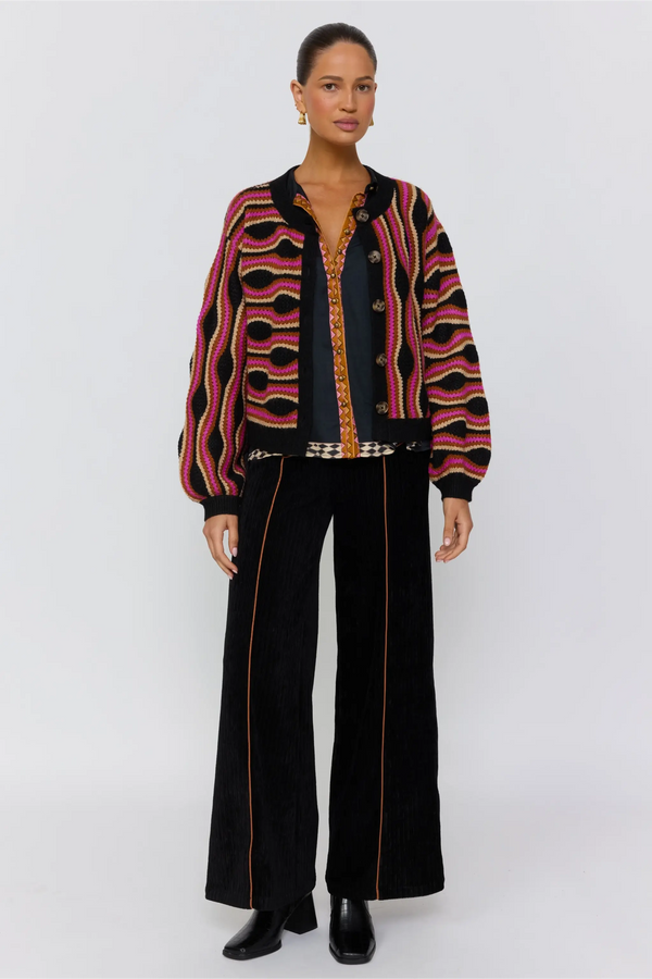 Woman wearing a patterned jacket and black pants on a white background