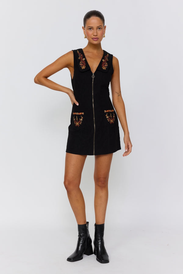 Woman wearing a black dress with floral embroidery on a white background