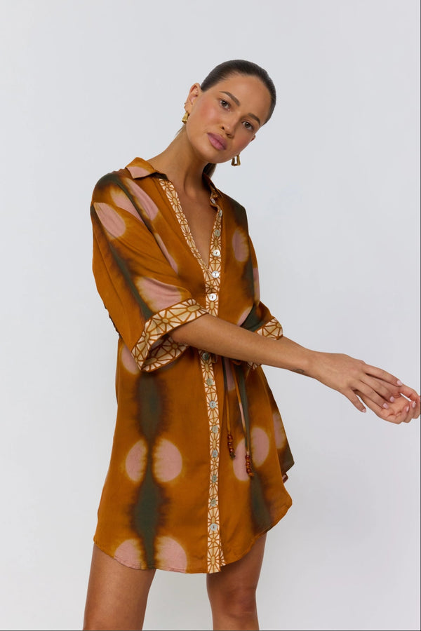 Woman wearing a patterned dress with sheer sleeves on a white background