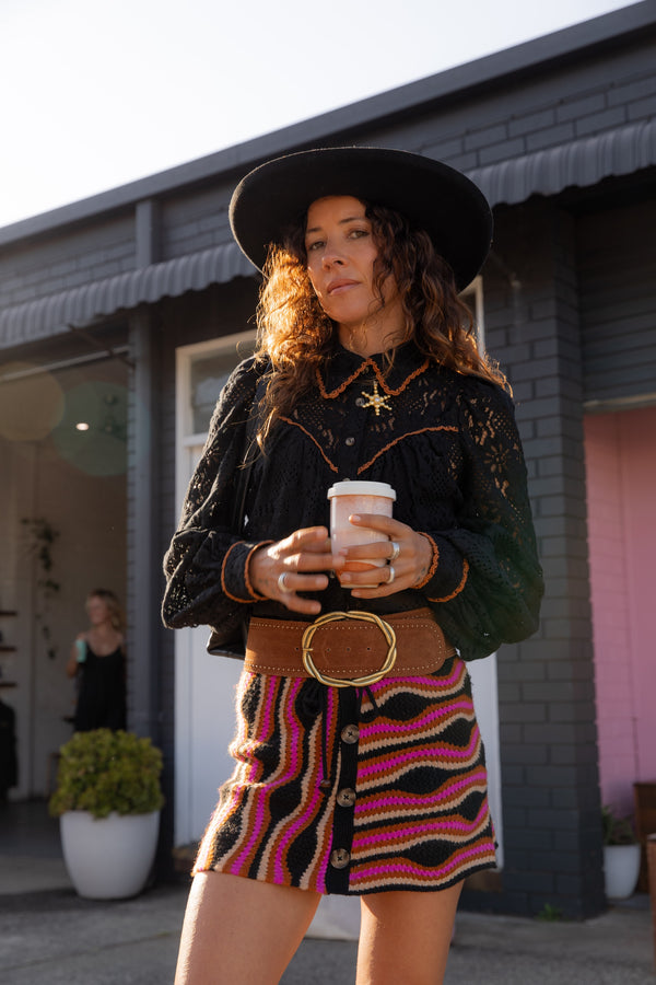 Woman in a stylish outfit holding a coffee cup outdoors.