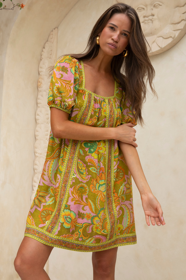 Woman wearing a colorful patterned dress against a neutral background