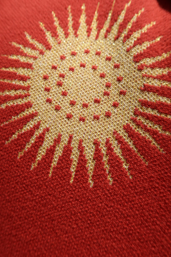 Embroidered sun design on a red fabric background
