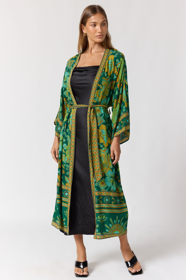 Woman wearing a green patterned kimono over a black dress on a white background