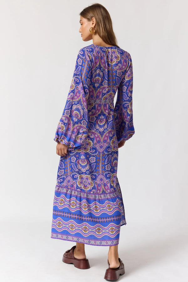 Woman wearing a long, patterned dress with a white background