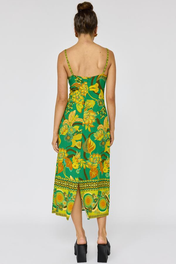 Woman wearing a green and yellow floral dress on a white background