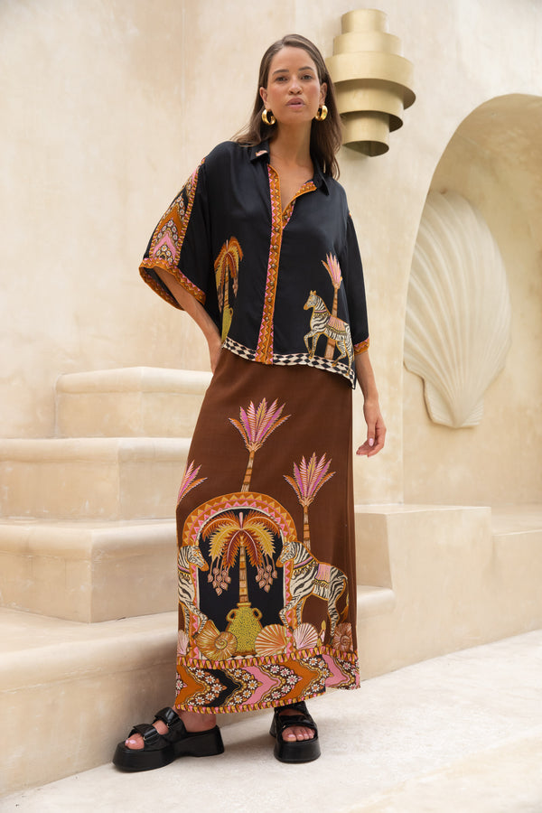 Woman wearing a black and brown patterned outfit standing on a staircase.