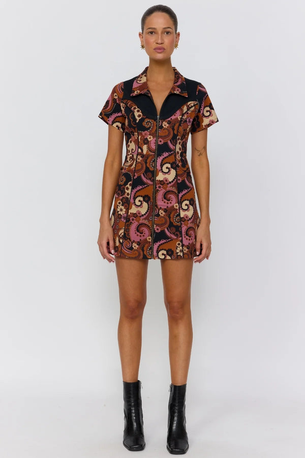 Woman wearing a patterned dress with black boots on a white background