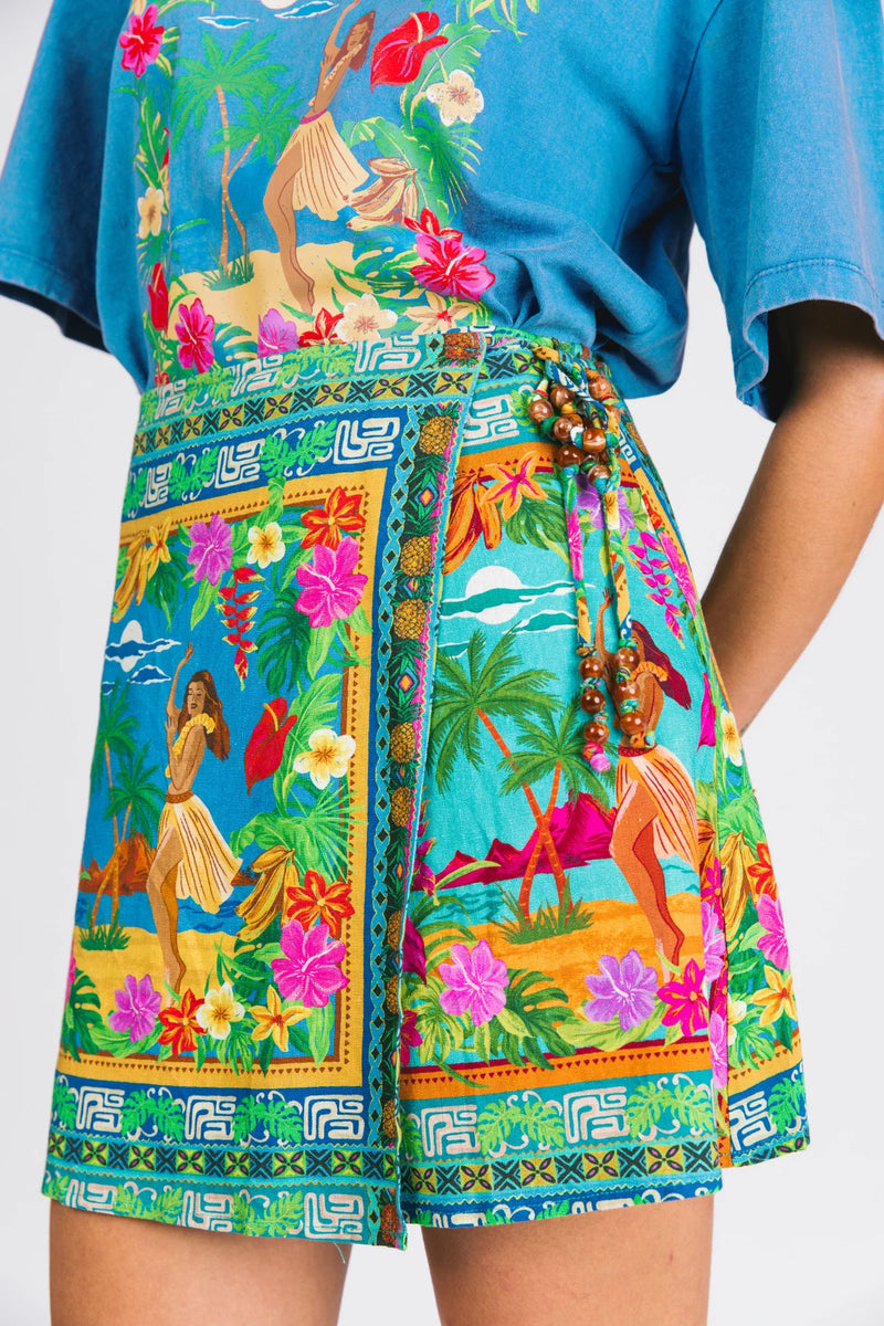 Person wearing a colorful tropical-themed apron over a blue shirt.