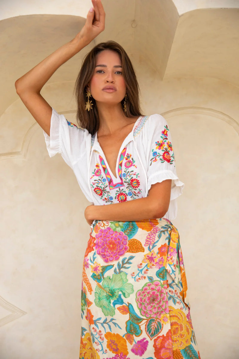 Woman wearing a colorful floral dress against a beige background