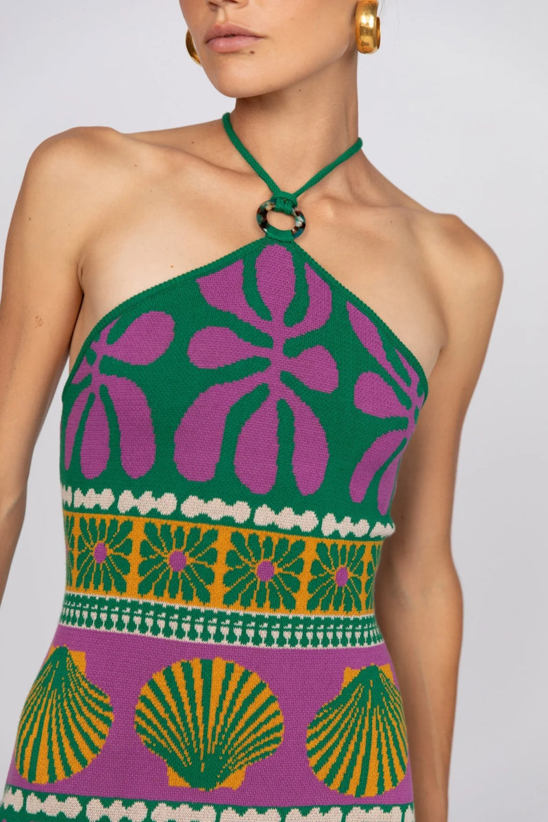 Woman wearing a green and purple patterned halter top with a white background
