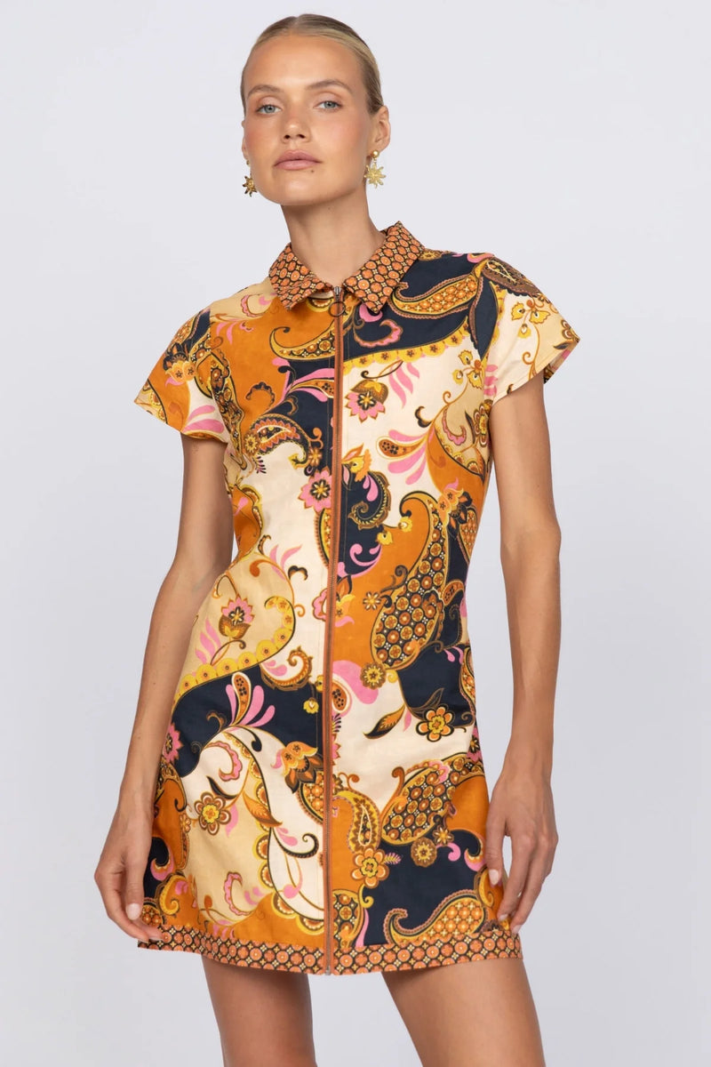 Women wearing black, brown and gold mini dress, standing against a white background