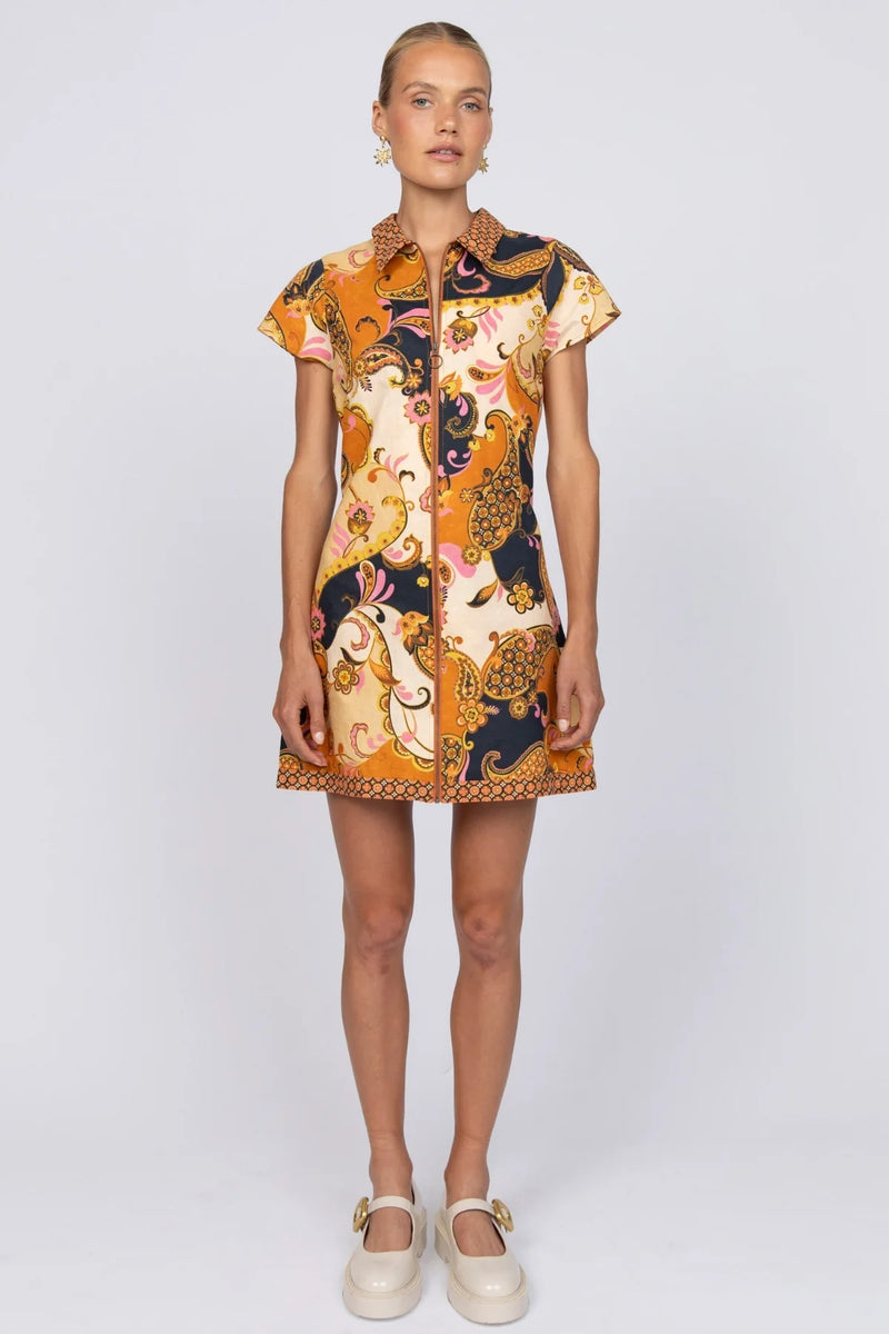 Model wearing a patterned dress on a white background